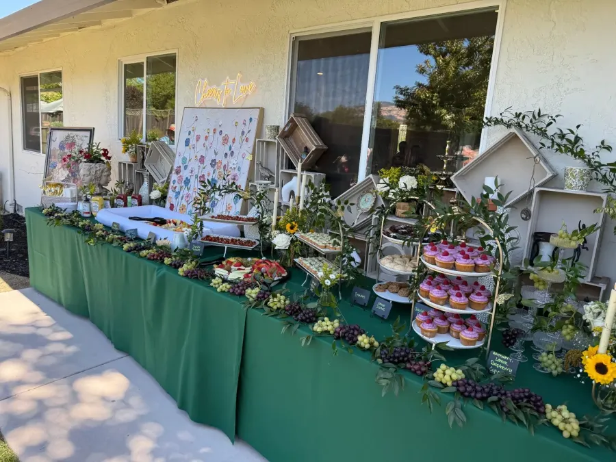 Shower sweets and grazing spread softened with roses and greenery set among cupcakes and fruit — shower floral styling from Belmont catering