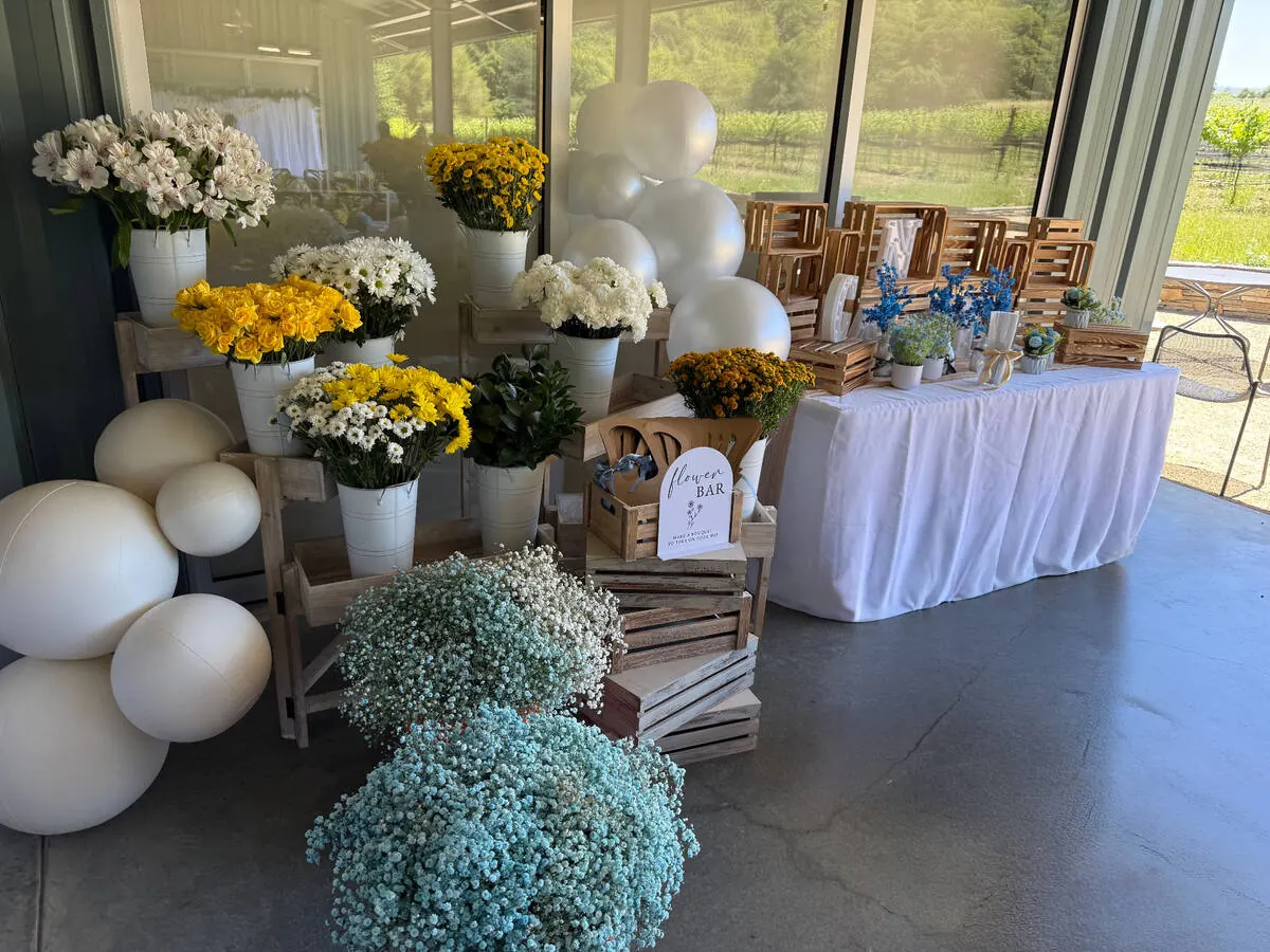 Bloom bar stocked with yellow roses, daisies and baby's breath alongside ribbon and paper so guests wrap their own bouquets — bloom bar experience from Burlingame catering