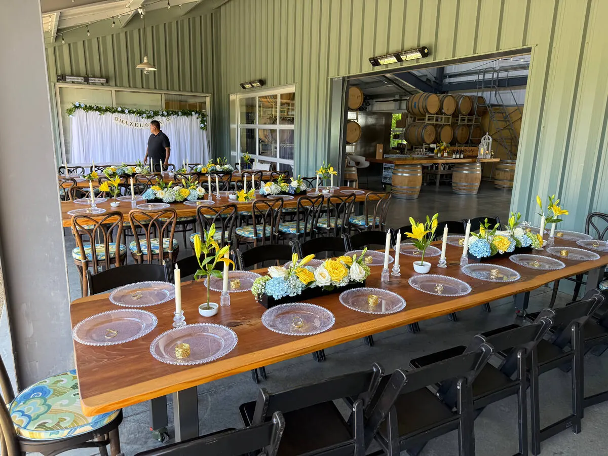 Banquet table carrying lily, hydrangea and rose arrangements between slim tapers along its full length — centerpiece design for Peninsula catering receptions in San Mateo County