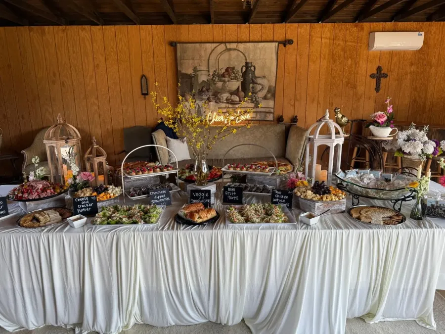 Grazing table of cured meats, tea sandwiches and fruit tarts punctuated by low bud vases down its run — floral-styled grazing for Millbrae catering